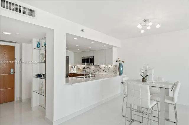 a kitchen with a dining table chairs and refrigerator