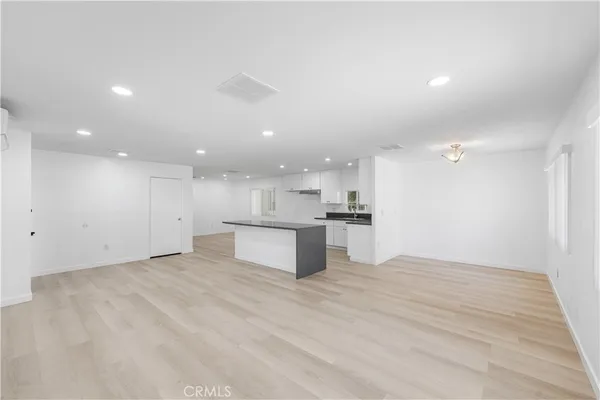 a large kitchen with stainless steel appliances granite countertop a stove a refrigerator a sink and white cabinets with wooden floor
