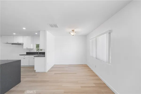 a open kitchen with white cabinets and wooden floor