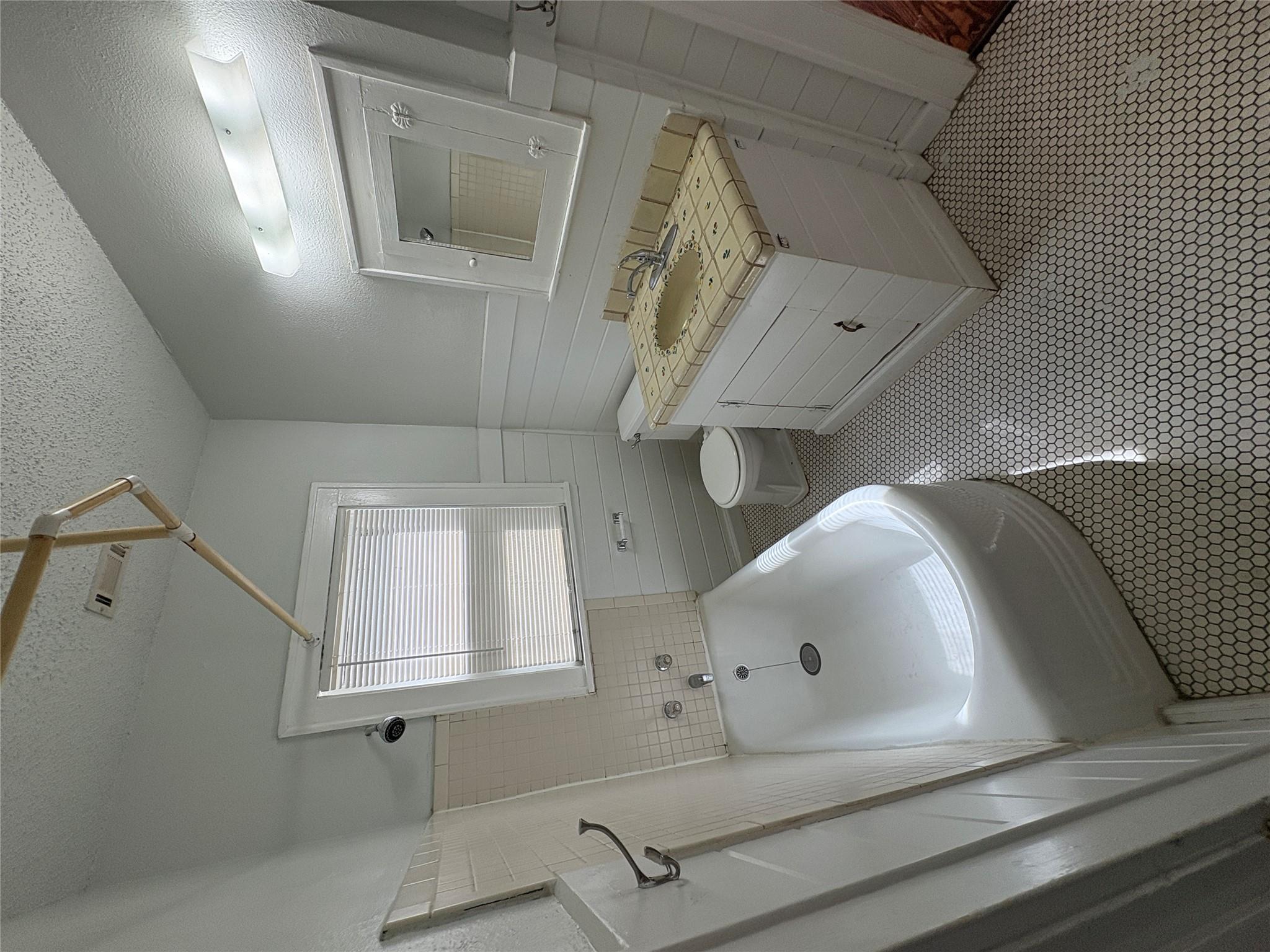 915 West 29th Street Austin, TX 78705 - Photo 5 of 20 Bathroom featuring a white bathtub, hexagon tile flooring, white vanity with a tiled countertop, and a window with blinds