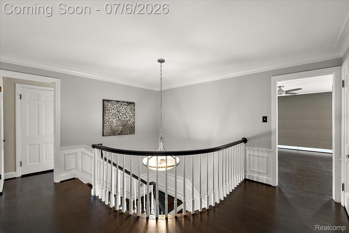 1051 Devonshire Road Grosse Pointe, MI 48230 - Photo 32 of 98 Upper-level landing featuring dark wood-finish flooring, white wainscoting, and a curved staircase with white balusters and a dark handrail