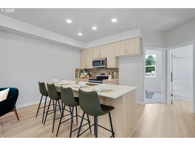 a kitchen with stainless steel appliances a dining table chairs and a refrigerator