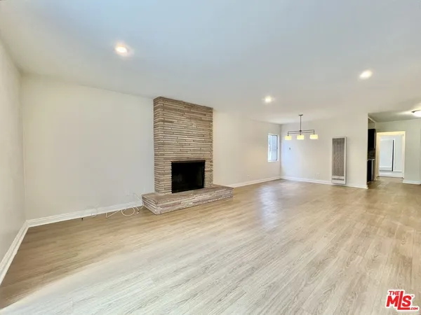 a view of an empty room with wooden floor and a fireplace