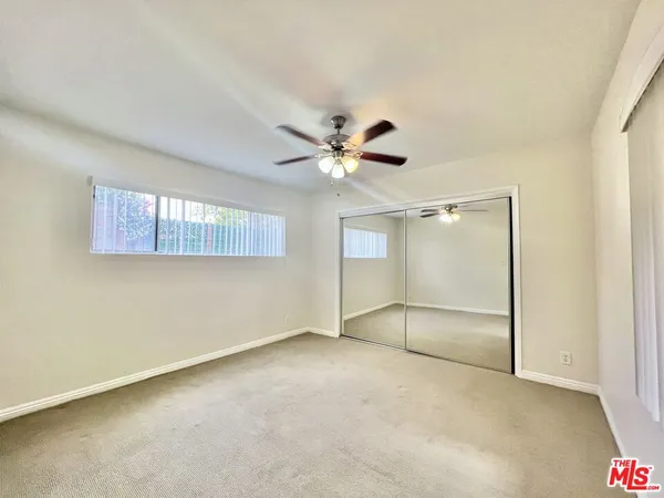 an empty room with windows and fan