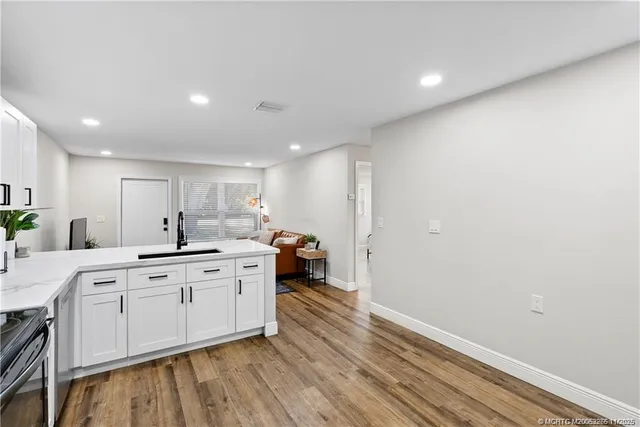 a large kitchen with a sink and dishwasher a stove with wooden floor