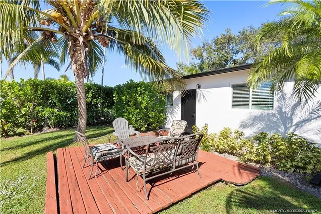a view of a backyard with chairs potted plants and large tree