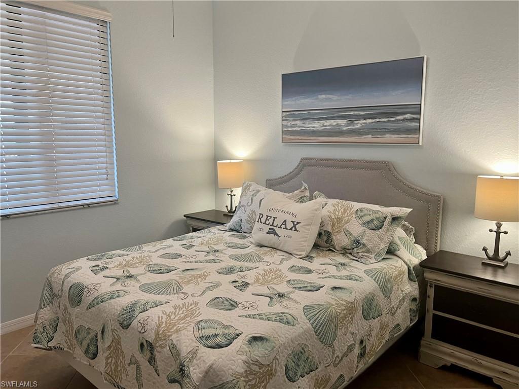 9715 Acqua Court, Unit 125 Naples, FL 34113 - Photo 21 of 24 a large bed sitting in a bedroom next to a lamp