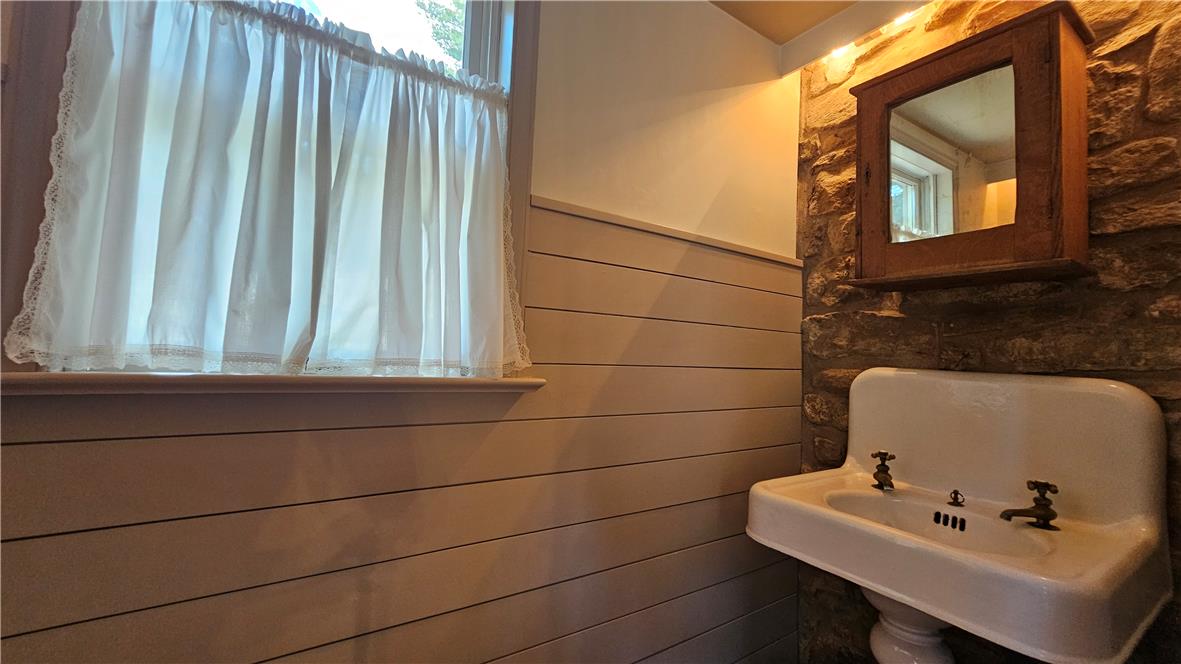 585 Buttermilk Road Hellertown, PA 18055 - Photo 18 of 82 A classic pedestal sink and rustic stone wall create a charming powder room.