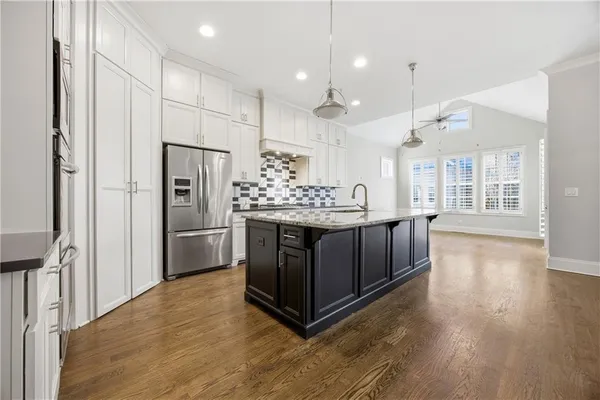 a kitchen with stainless steel appliances kitchen island a refrigerator and a view of living room