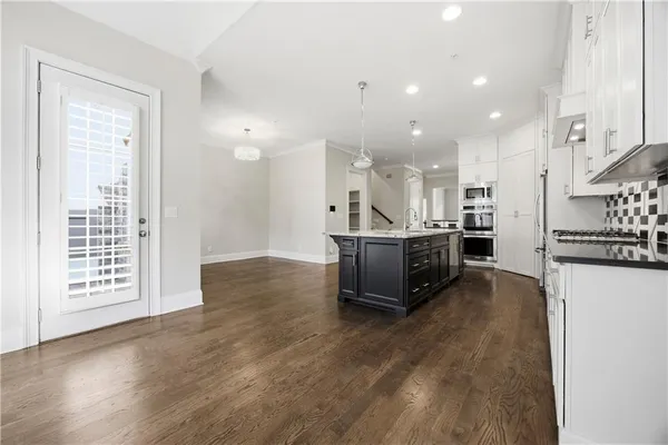 a living room with stainless steel appliances kitchen island granite countertop a refrigerator and a sink