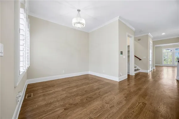 a view of an empty room with window and wooden floor