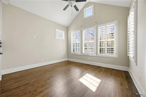 an empty room with wooden floor and windows