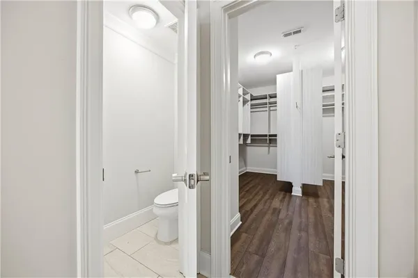 a view of a hallway with wooden floor and a bathroom