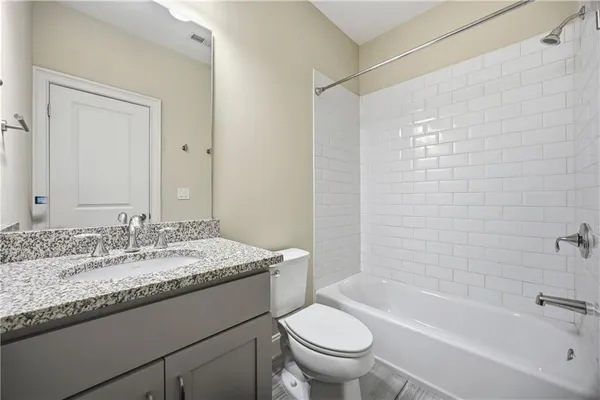 a bathroom with a granite countertop sink a toilet and bathtub