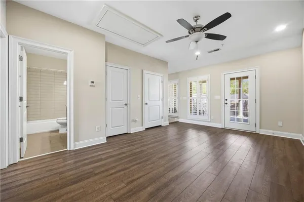 a view of an empty room with wooden floor and a ceiling fan