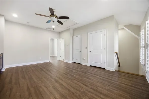 a view of an empty room with wooden floor and a ceiling fan