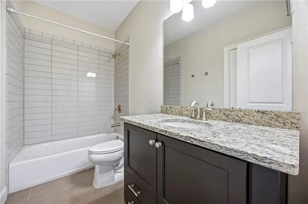 a bathroom with a granite countertop sink a toilet and bathtub