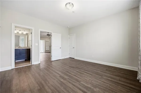 a view of an empty room with wooden floor and a bathroom