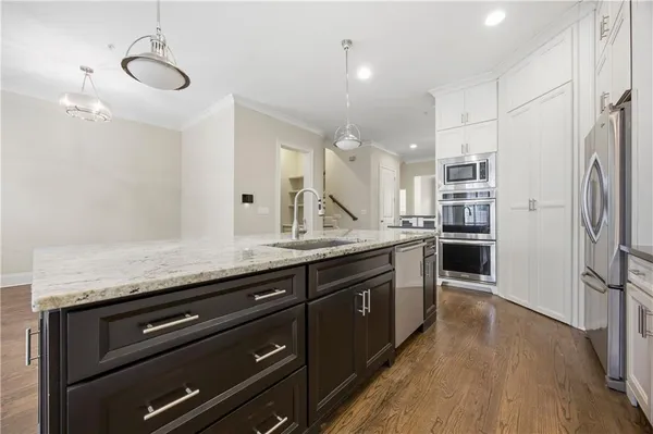 a kitchen with granite countertop a refrigerator a stove and wooden floor
