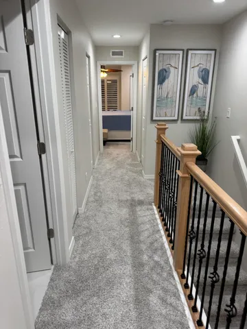 a view of a hallway to a livingroom with wooden floor and furniture