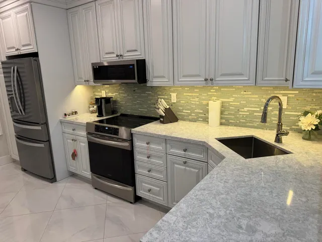 a kitchen with granite countertop a stove sink and refrigerator