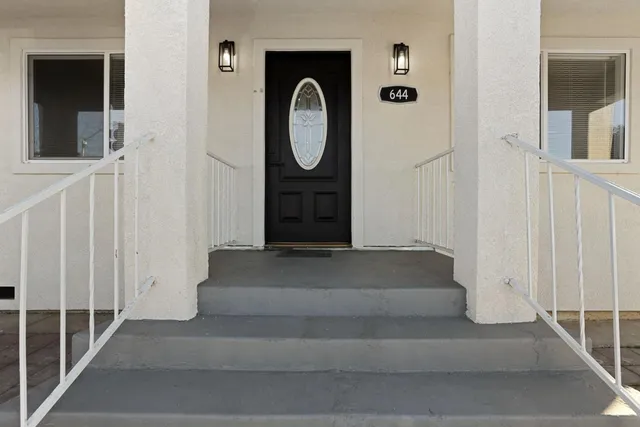 a view of a white house with a small yard and plants next to a road