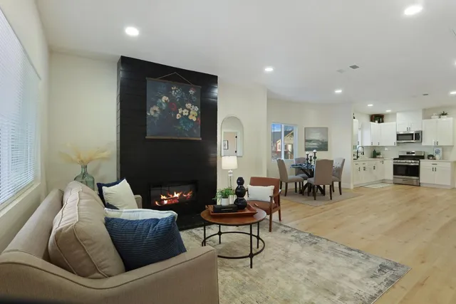 a living room with furniture a large window and wooden floor