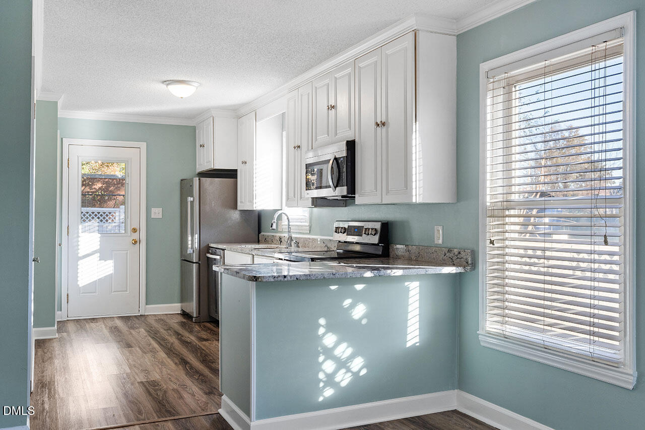 2306 Stafford Avenue, Unit D Raleigh, NC 27607 - Photo 8 of 24 a kitchen with stainless steel appliances granite countertop a refrigerator a stove a sink and dishwasher with wooden floor