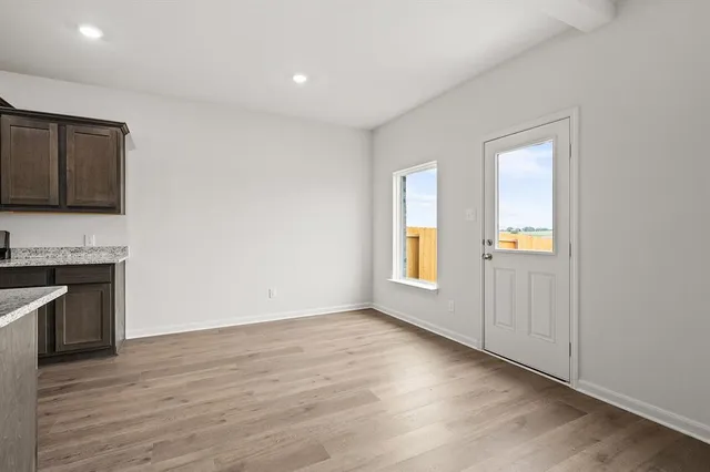 a view of an empty room with window and wooden floor