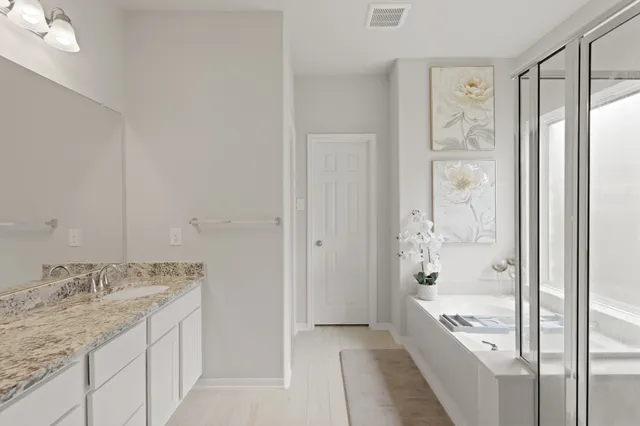 a bathroom with a granite countertop sink a mirror and a bathtub
