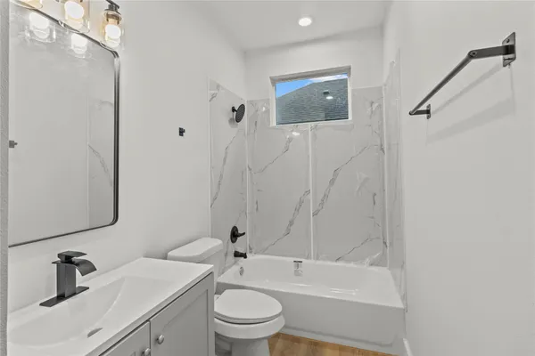 a bathroom with a toilet a sink a mirror and bathtub