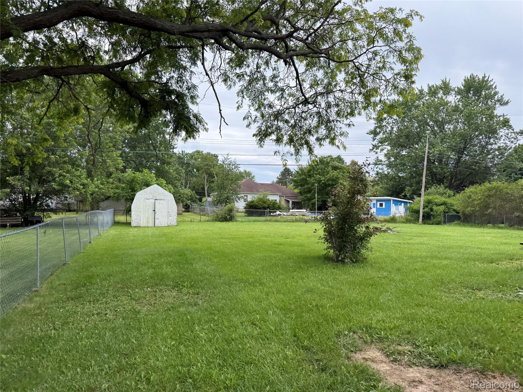 5347 Mapletree Drive Flint, MI 48532 - Photo 2 of 10 Expansive green lawn with a chain-link fence bordering the property