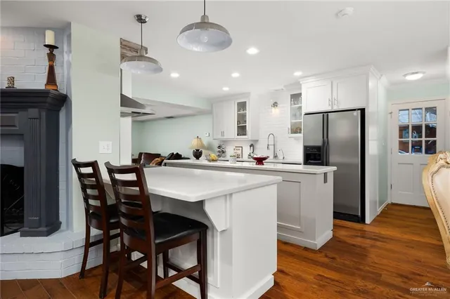 a kitchen with stainless steel appliances a dining table chairs refrigerator sink and cabinets