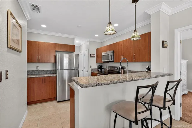 a kitchen with stainless steel appliances granite countertop a refrigerator a stove a sink a center island a dining table and chairs with wooden floor