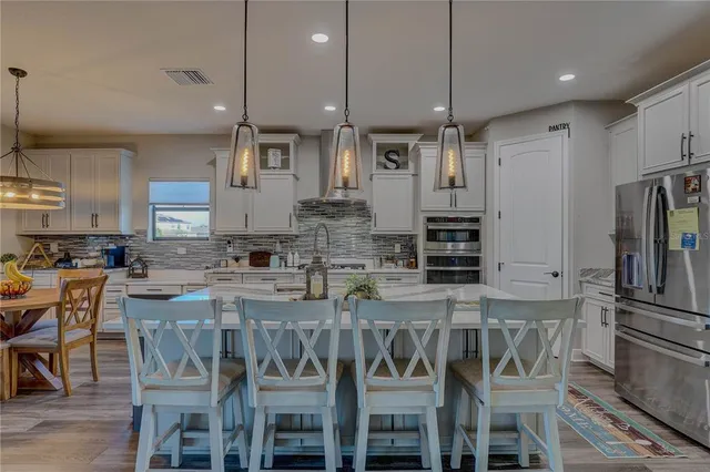 a kitchen with stainless steel appliances granite countertop a kitchen island hardwood floor sink stove dining table and chairs