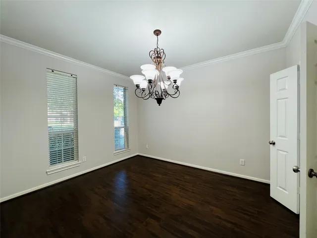 a view of a room with wooden floor chandelier and windows