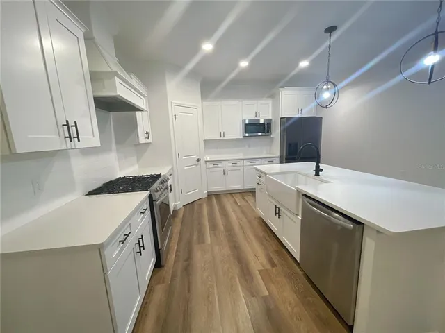 a kitchen with a sink a counter top space stainless steel appliances and cabinets