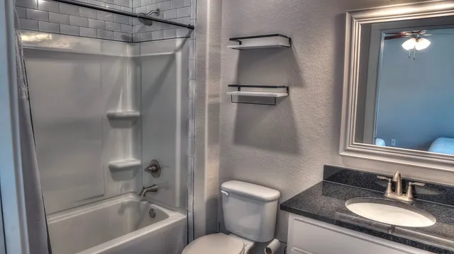 a bathroom with a granite countertop sink toilet and shower