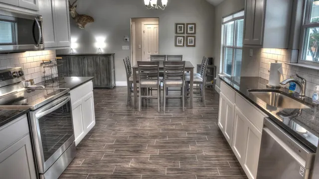 a kitchen with granite countertop a sink a counter top space and stainless steel appliances