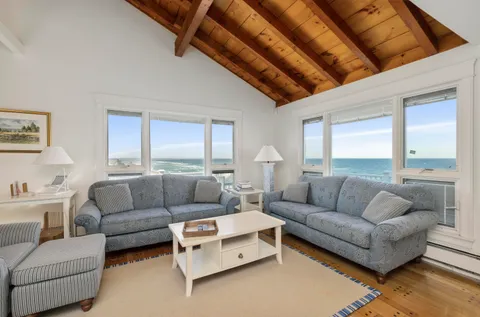 a living room with couches a fireplace and a large window with wooden floor