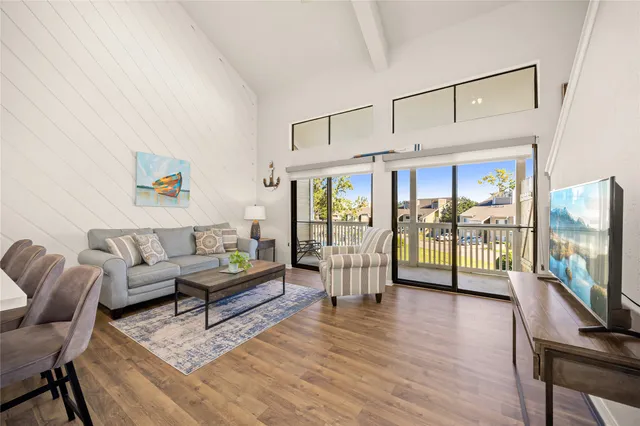 a living room with furniture a flat screen tv and a floor to ceiling window