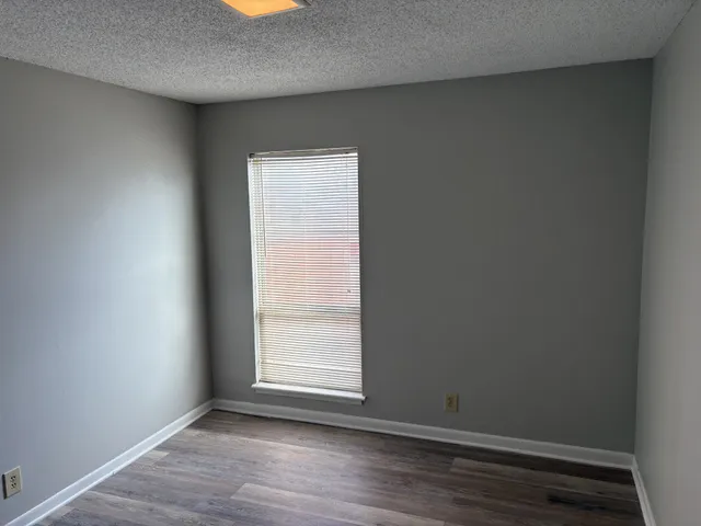 a view of an empty room with wooden floor and closet