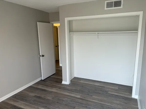 a view of an empty room with wooden floor and closet