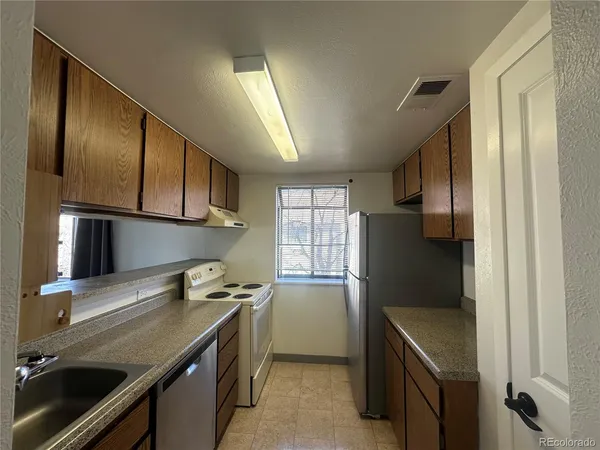 a kitchen with stainless steel appliances granite countertop a refrigerator a sink and wooden cabinets