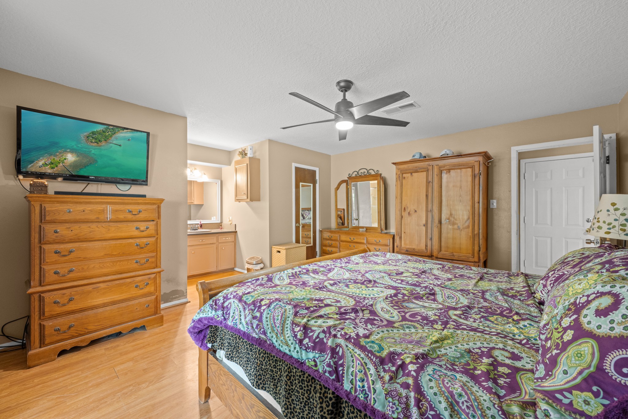 15602 Fir Road Santa Fe, TX 77517 - Photo 18 of 42 Generously sized primary suite featuring wood-look flooring, modern ceiling fan, and a spacious layout with room for additional furnishings. The ensuite vanity area and abundant storage enhance both comfort and everyday functionality.