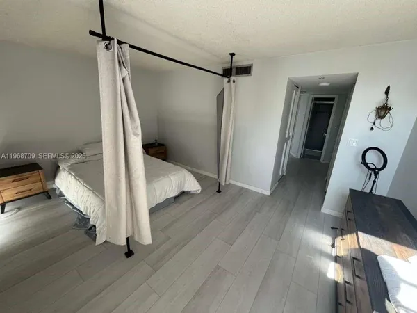 a view of front door and bedroom with wooden floor