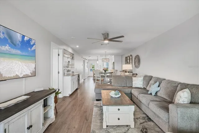 a kitchen with stainless steel appliances a refrigerator a stove a sink a dining table and chairs with wooden floor