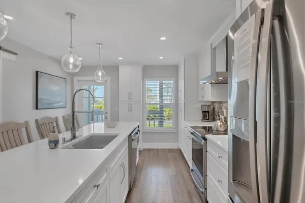 a large kitchen with kitchen island a stove a sink a chimney and cabinets