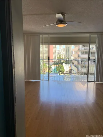 a view of empty room with wooden floor and fan