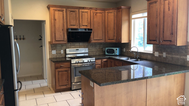 U-shaped kitchen featuring wood cabinetry, stainless steel range, and stone countertops